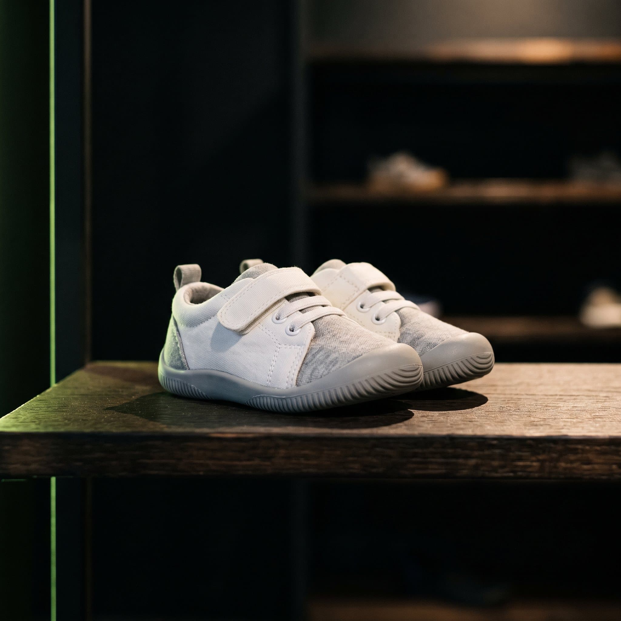 Dettaglio di un paio di sneakers da bambino piccolo esposte su una mensola in legno